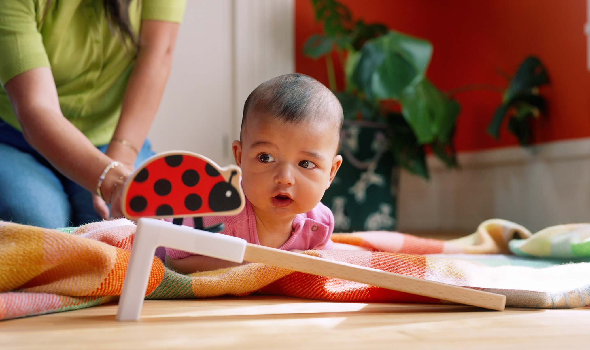 A baby watching the Lovevery Look at Me Ladybug on its wooden ramp, from Lovevery